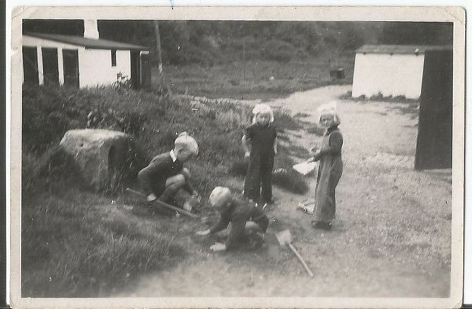 Jytte og Jørn-Ole Olsen, Mari-Ann Mortensen og Finn Hågensen leger på gårdspladsen. Året er 1949, og vi får et vue til vaskerhuset med de indbyggede lokum'er og Nielsens 